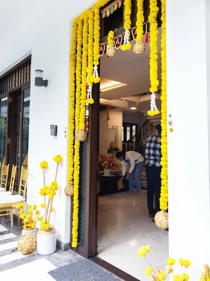 A beautiful doorway framed with hanging marigold garlands. Inside, our team is seen making the final touches, ensuring every detail is perfect for the ceremony.