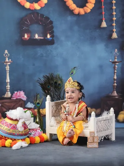 A wider view of one of my Baby Krishna setups. The deep blue background, marigold garlands, and traditional lamps create a rich, temple-like atmosphere for your little one's divine portrait.