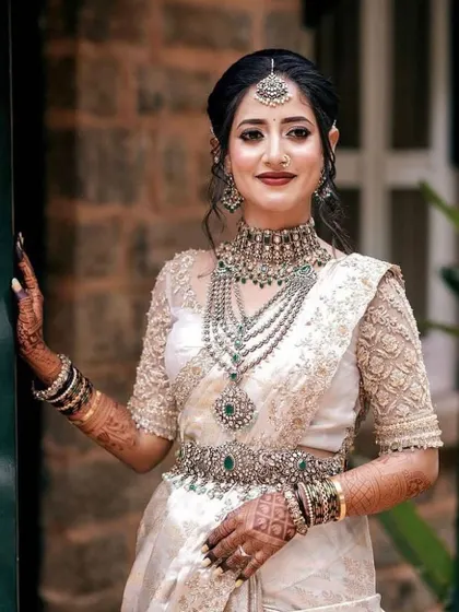 This bride looks radiant in her off-white saree and custom embroidered blouse. The intricate details and elegant design make it a perfect choice for a modern bride.