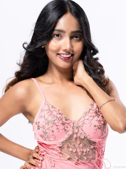 A smiling three-quarter portrait of a model in a pink dress.