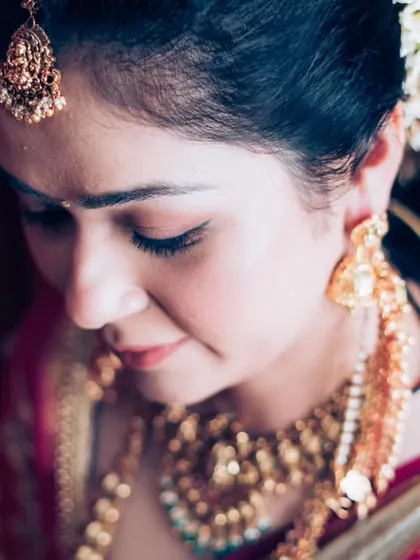 A close-up shot of the bride's serene expression as her hair is styled with traditional flowers.