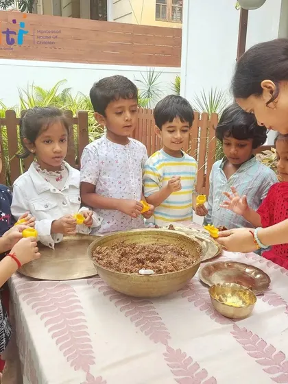 A teacher guides children as they learn to use molds to shape the modak dough. This activity refines their fine motor skills and introduces them to cultural traditions.
