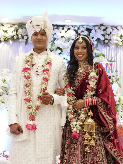 A classic portrait of a newly married couple in their stunning red and white wedding attire.
