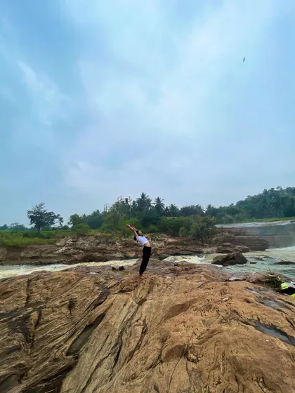A wider shot of the Hasta Uttanasana pose, showing how the body can harmonize with the grand scale of the natural landscape.