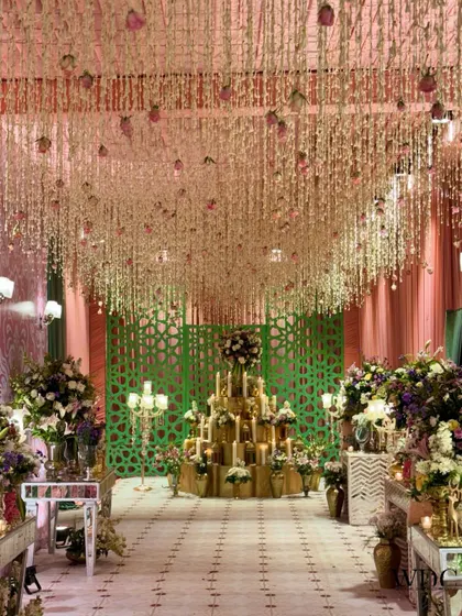 A 'Floral Serene Grandeur' reception entrance, where a ceiling of cascading white flowers and a candle-lit installation create an ethereal and magical pathway for guests.
