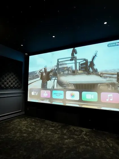 The vibrant colors of the movie on screen contrast beautifully with the dark, classic interior of this Kanchipuram home cinema.