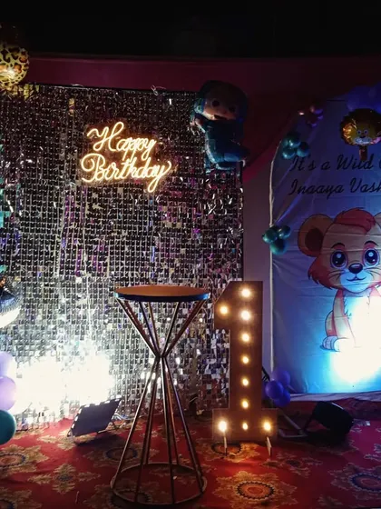 A 'Wild One' jungle theme for a first birthday, combining a silver shimmer wall with a custom character backdrop and leopard-print balloons.