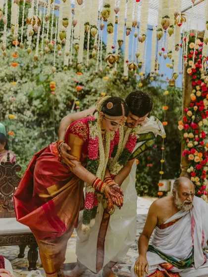 A beautiful ritual moment from the wedding, with the bride in a traditional red saree.