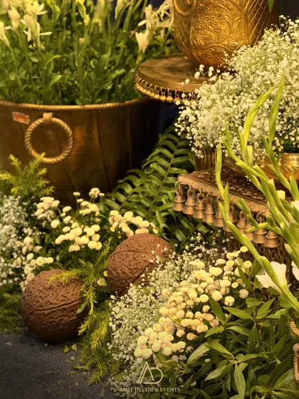 A close-up of the floral arrangements, showing a mix of baby's breath, gladiolus, and coconuts in traditional brass and copper pots.
