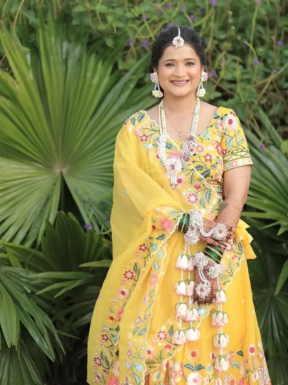 A full-length shot of the Haldi bride, showing how the floral jewellery complements her yellow embroidered lehenga.