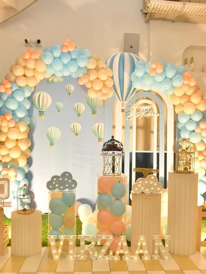 Up, up, and away with this hot air balloon themed decor. The setup features a large balloon arch, light-up letters, and hot air balloon props to create a sense of adventure and wonder.