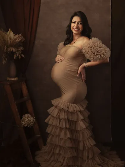 The rich textures of the gown and the warm, earthy backdrop come together to create a portrait that is both glamorous and deeply soulful.