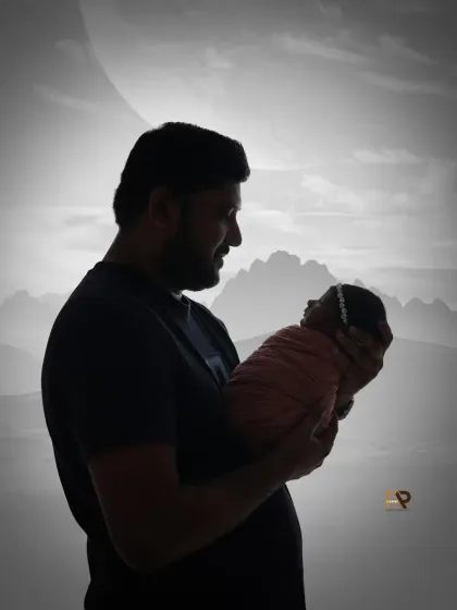 A black and white silhouette of a father holding his newborn baby. This artistic and timeless photo emphasizes the emotional connection and tenderness of the moment.