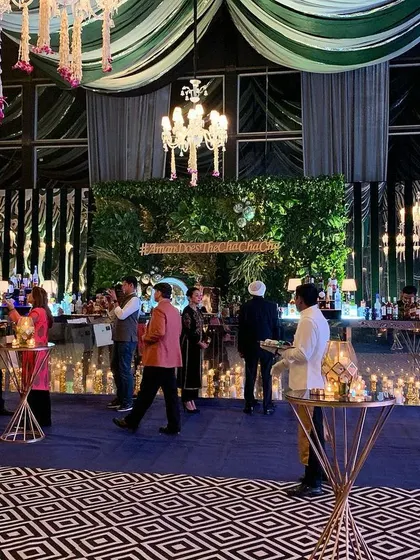 The bar is often the heart of a cocktail party. For this event, I designed a statement bar with a lush green backdrop, framed by candlelit stands and positioned under elegant chandeliers to create a central hub for guests.