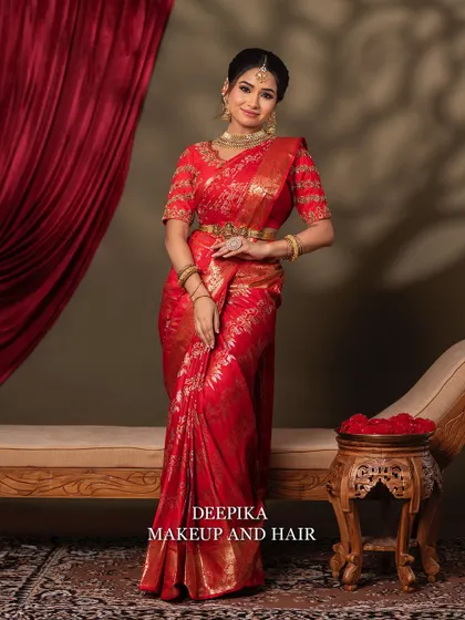 A full-length view of the bride seated on a traditional chaise lounge, looking regal and elegant in her red bridal attire.