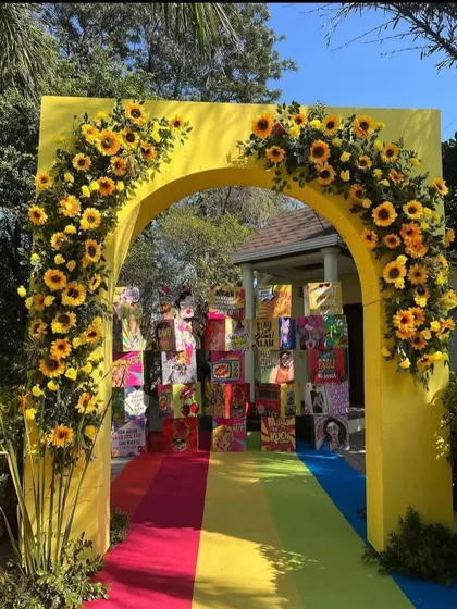 A cheerful yellow entrance arch decorated with sunflowers, leading to a quirky backdrop made of snack food boxes. This is a great example of our personalized and fun decor.