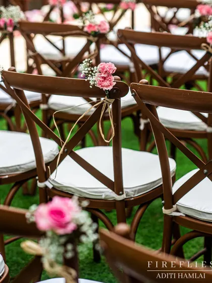 Simple yet elegant chair decor, with a small posy of pink carnations and baby's breath tied to the back of each chair.