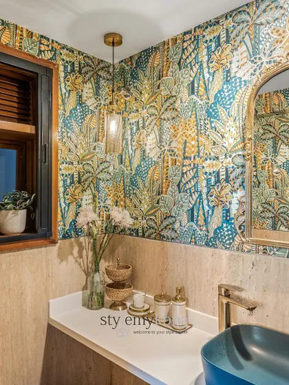 Another angle of the cloakroom, showing the beautiful interplay of the tropical wallpaper, travertine stone, and gold fixtures.