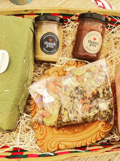 A close-up of my Diwali hamper, showcasing the eco-friendly packaging and the delicious treats inside. You can see the nut butters, trail mix, and a loaf of bread wrapped in a leaf.