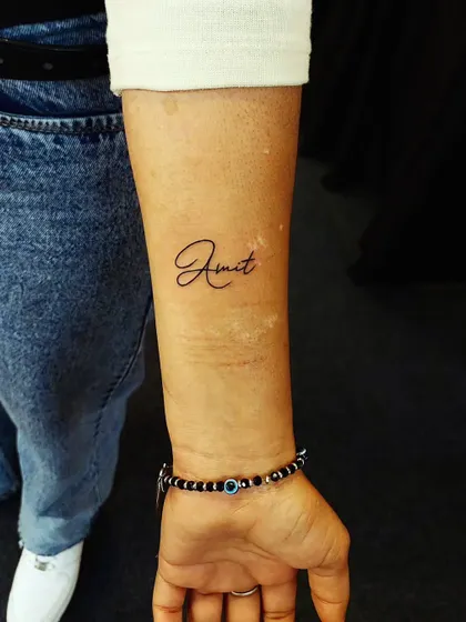 A simple and elegant name tattoo, 'Amit', in a clean cursive script. A perfect way to honor someone special.