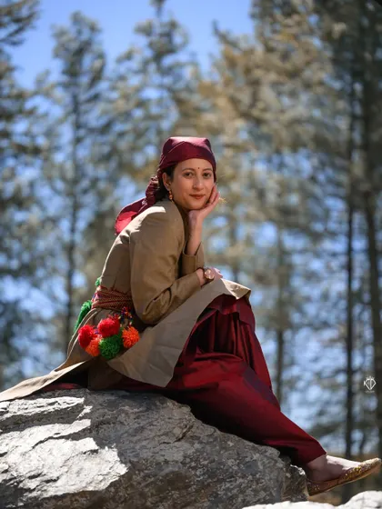 Another angle of the woman seated on the boulder, highlighting the colorful details on the belt of her traditional dress.