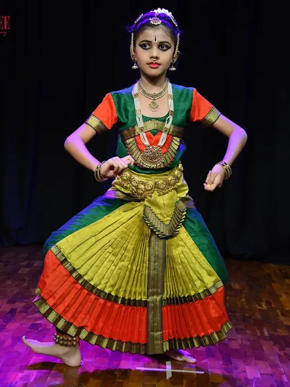 A young student in her full Bharatanatyam costume, ready for her performance. We focus on building a strong foundation and love for the art form from an early age.