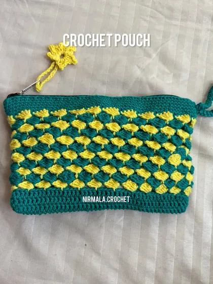 A close-up of our textured pouch in a vibrant green and yellow color combination, complete with a flower charm on the zipper.