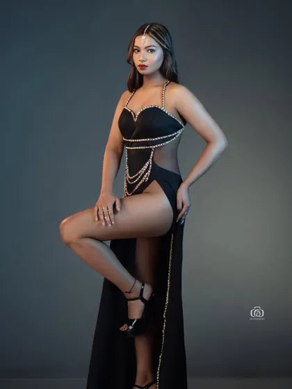 A dynamic pose in a black, pearl-embellished gown. The studio lighting highlights the intricate details and the model's strong form, making for a striking and sophisticated fashion portrait.
