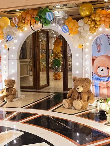 A grand entrance decorated with a hot air balloon and teddy bear theme, using a warm color palette of orange, yellow, and gold.