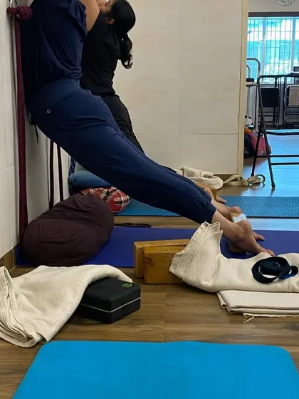 Using the wall and props for a supported stretch. This variation helps to decompress the spine and lengthen the back of the legs safely.