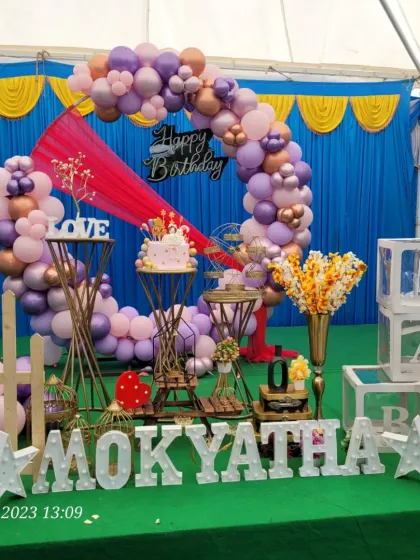 This shot shows the cake placed at the center of the celebration, surrounded by elegant props and a vibrant balloon arch.
