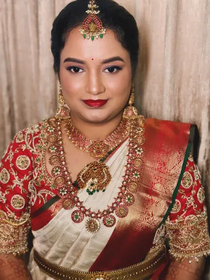 A traditional reception look for Sneha in a classic white and red Kanjivaram saree, complete with a bold red lip and temple jewellery.