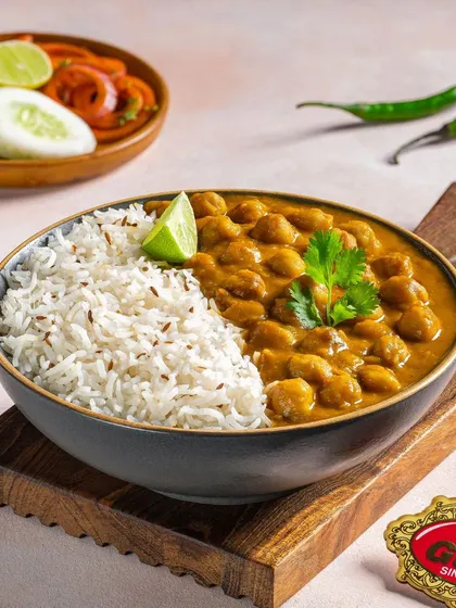 A comforting bowl of Chole Chawal, garnished with fresh coriander and a slice of lime.