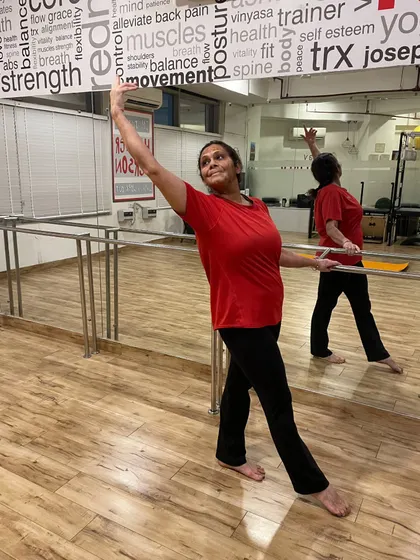 A member gracefully performs a ballet-inspired move at the barre, showing that strength and elegance go hand-in-hand.