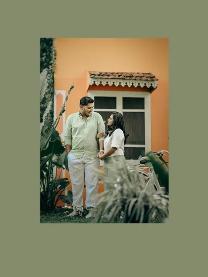 A couple shares a quiet moment in front of a colorful house, framed in a warm green border.