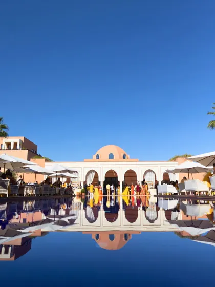 The stunning poolside setting for the Haldi ceremony at the Oberoi Marrakech, with the hotel's beautiful architecture reflected in the water.