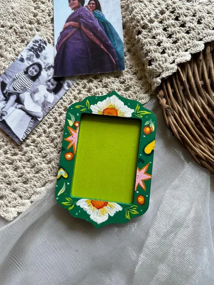 A floral-themed photo frame magnet, with white flowers against a bold green background.