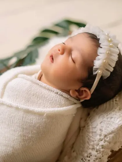 A close-up view of a perfectly wrapped newborn. The texture of the wrap and the soft headband add delicate details to this simple and pure portrait.