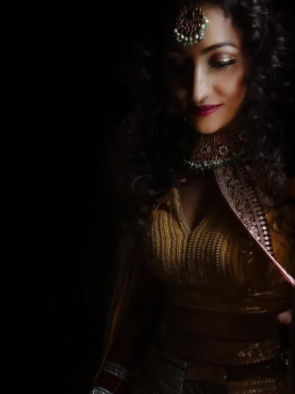 A striking low-light portrait of a bride, showcasing her intricate jewelry and makeup. We use shadows and light to create a sense of mystery and elegance.