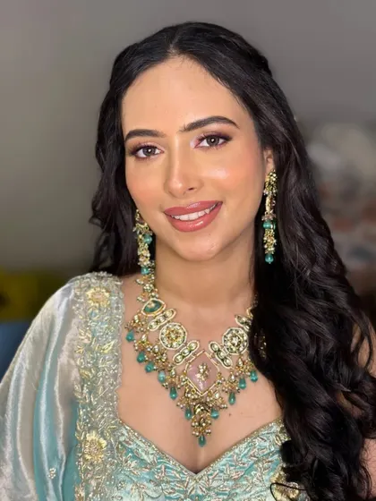 A beautiful morning Roka bride. The makeup is fresh and luminous, with a soft pink lip and defined eyes to complement her pastel blue outfit and emerald jewelry.