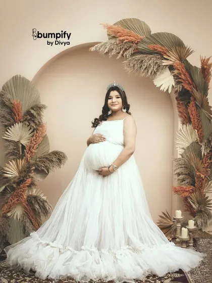 A stunning solo portrait of the mom-to-be in the same setup. She looks like a true queen, cradling her bump with a gentle smile.