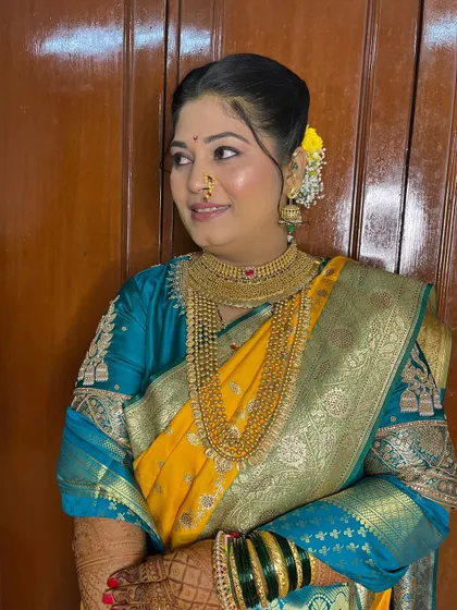 A profile view showing the traditional hairstyle adorned with fresh yellow flowers, complementing her saree perfectly.