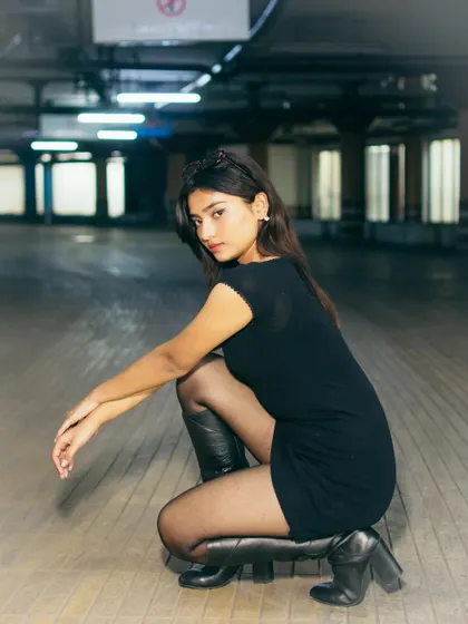 A crouching pose from the parking lot shoot, offering a different perspective. The cool tones of the fluorescent lights and the subject's direct gaze create an intense and engaging portrait.
