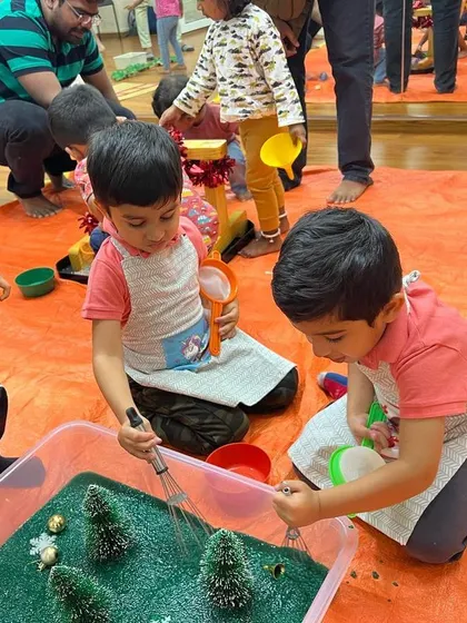 A "Chrismessy" party is the best kind of party. Here, two friends are exploring a winter wonderland sensory bin, complete with fake snow and little trees, perfect for imaginative holiday play.