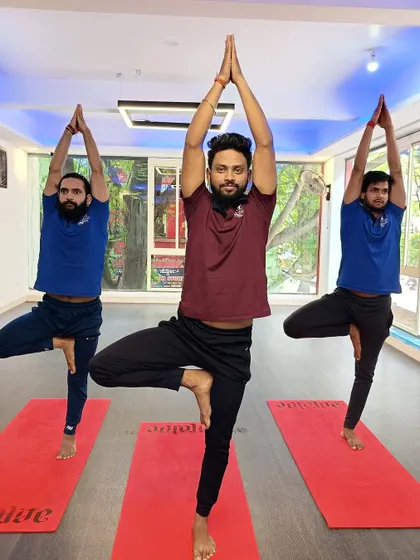 Three instructors hold Vrksasana (Tree Pose), demonstrating the stability and grace that comes with practice.