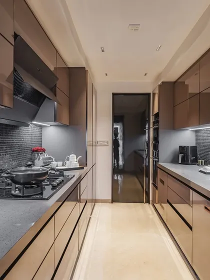 A sleek parallel kitchen with brown acrylic cabinets and a mosaic tile backsplash, creating a warm and inviting atmosphere.