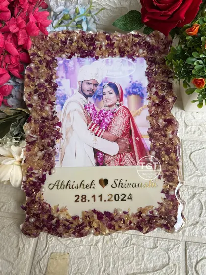 This 9x12 inch resin frame features a border made entirely of preserved varmala flowers. The couple's photo is centered above their names and wedding date.