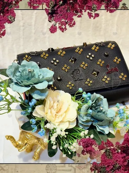 A close-up of the black studded handbag, framed by a floral border. This image highlights the beautiful texture of the bag and the delicate floral arrangement.