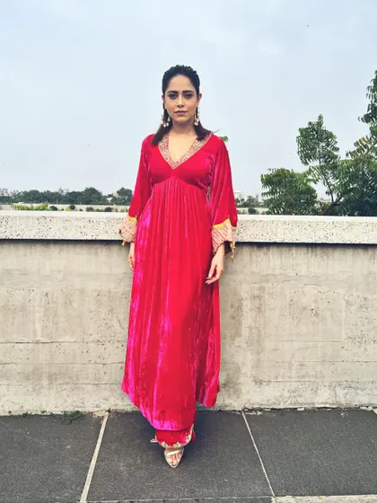 A full-length shot of Nushrratt's pink velvet suit. The embroidered sleeves and matching juttis complete this traditional yet trendy look.