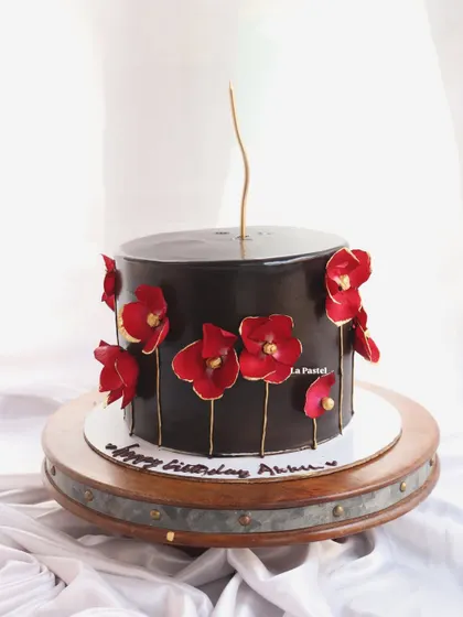 A bold and artistic design. This cake has a glossy black chocolate finish and is decorated with striking red wafer paper flowers with gold stems.